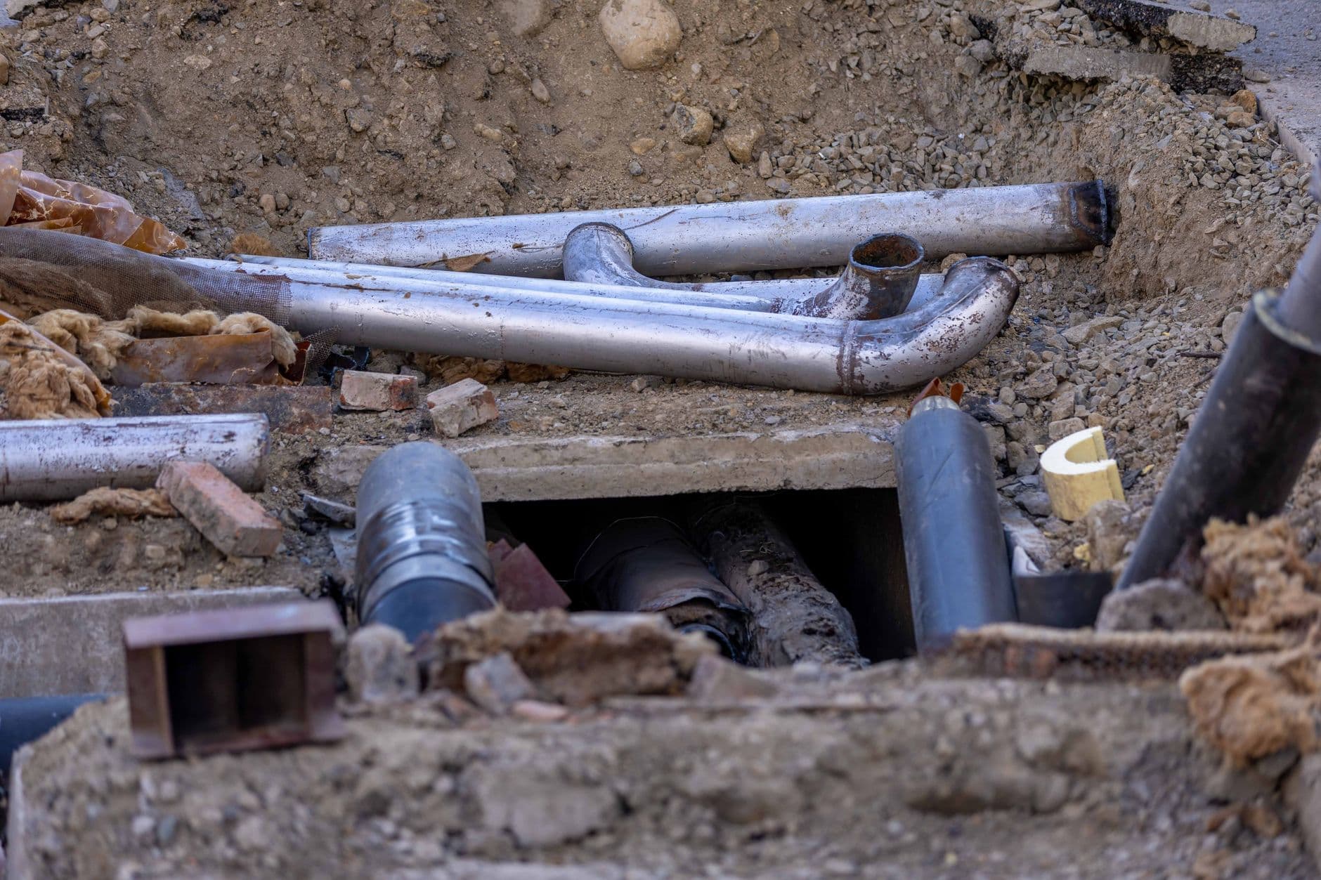 New perforated drain pipe being laid in an open trench at a work site.