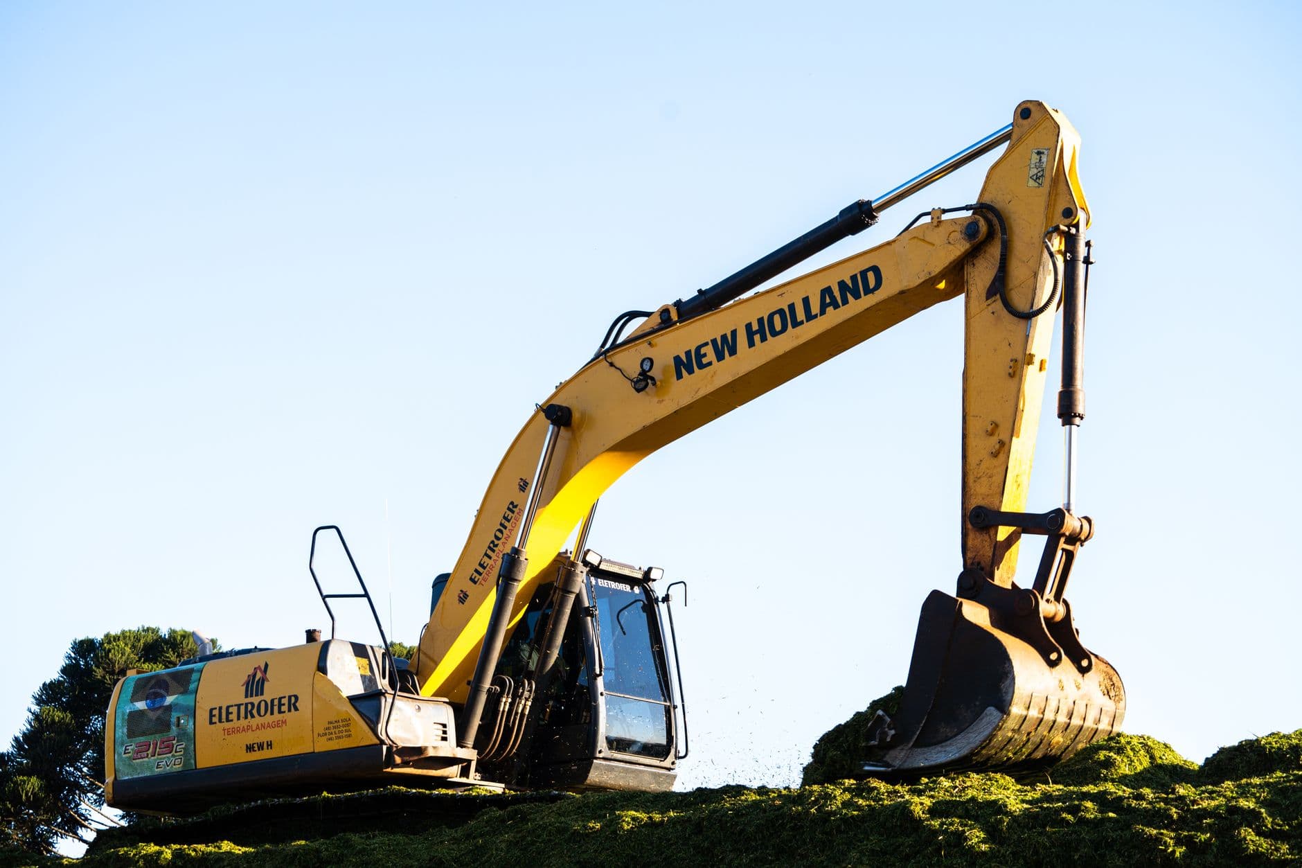 An excavator lifting soil away to expose a home foundation footing.